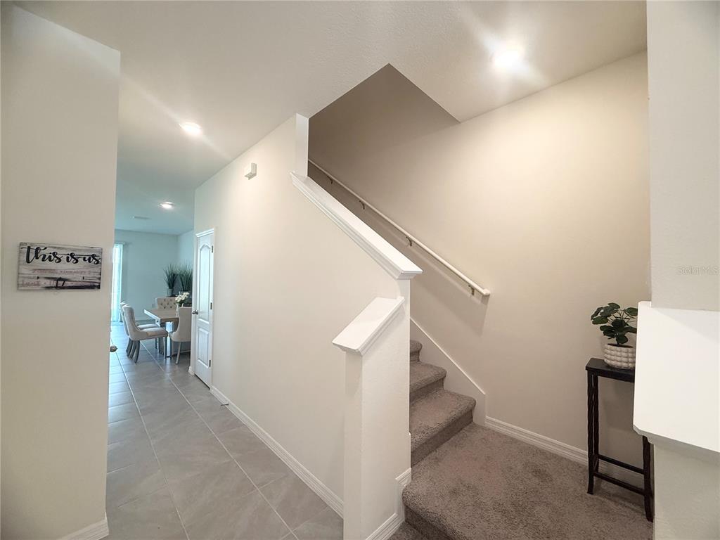 An interior view shows a carpeted staircase next to a tiled hallway leading to a dining area — 1503 ISLETA LOOP, KISSIMMEE, FL