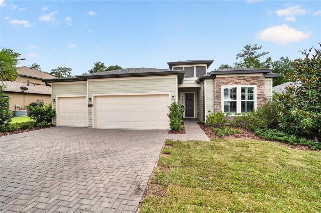 A single-story house with a three-car garage, stone accents, and a paved driveway — 4310 SE 11TH AVENUE, OCALA, FL