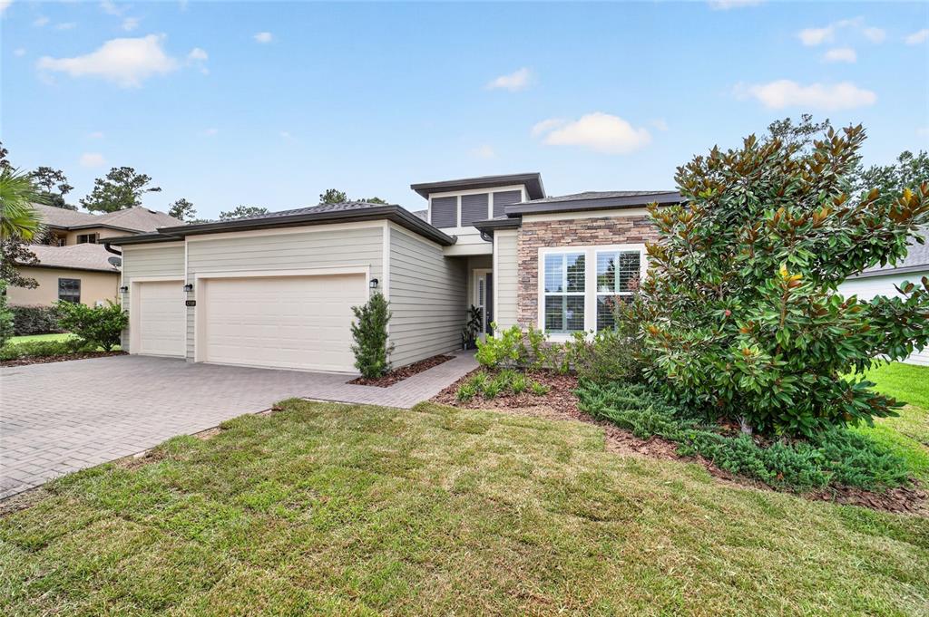 A single-story house features light siding, a stone facade, and a paved driveway — 4310 SE 11TH AVENUE, OCALA, FL