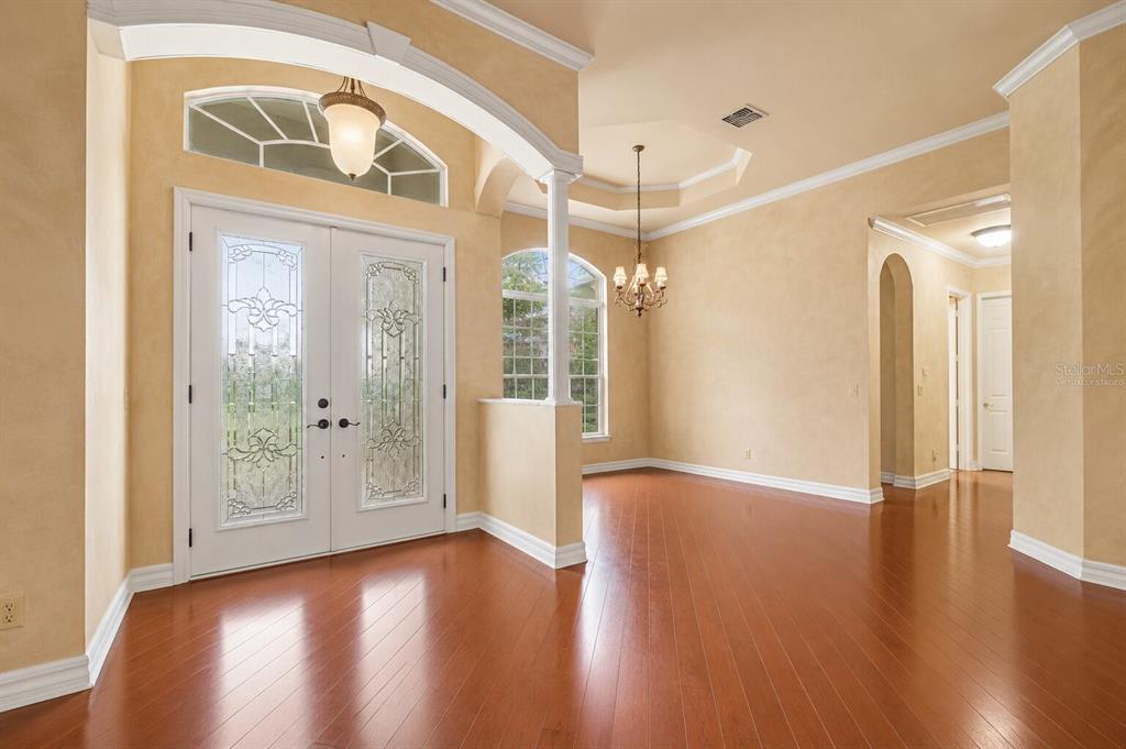 A spacious foyer features hardwood floors, a double-door entrance, and warm-toned textured walls — 20831 COPPERHEAD DRIVE, LEHIGH ACRES, FL