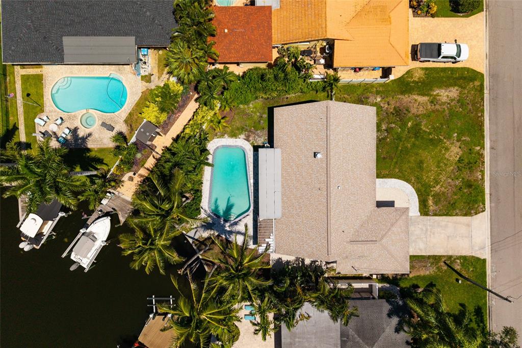 An aerial view shows a waterfront house with a pool, boat dock, and paved driveway — 3960 13TH WAY NE, ST PETERSBURG, FL