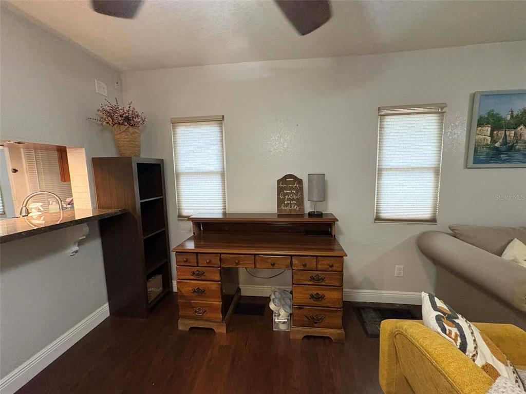 A room features a wooden desk, a tall bookshelf, two windows, and dark flooring — 1040 S OHIO AVE, LAKELAND, FL