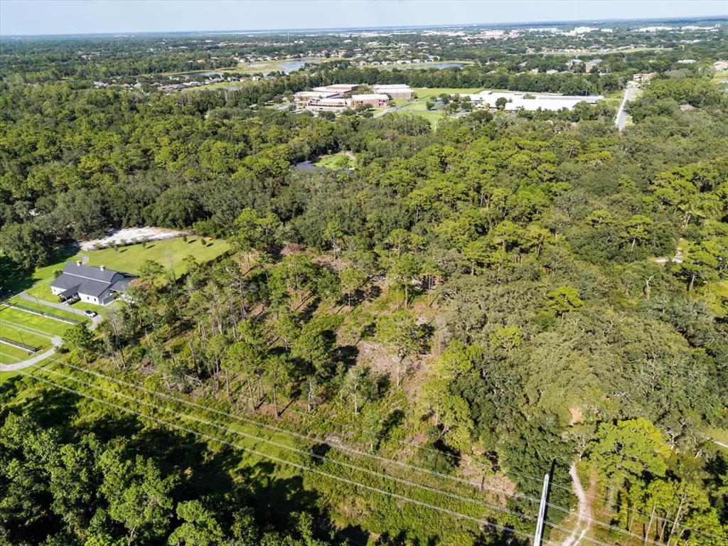 An aerial view shows a large, wooded lot with a building and power lines nearby — MARKHAM WOODS ROAD, LAKE MARY, FL