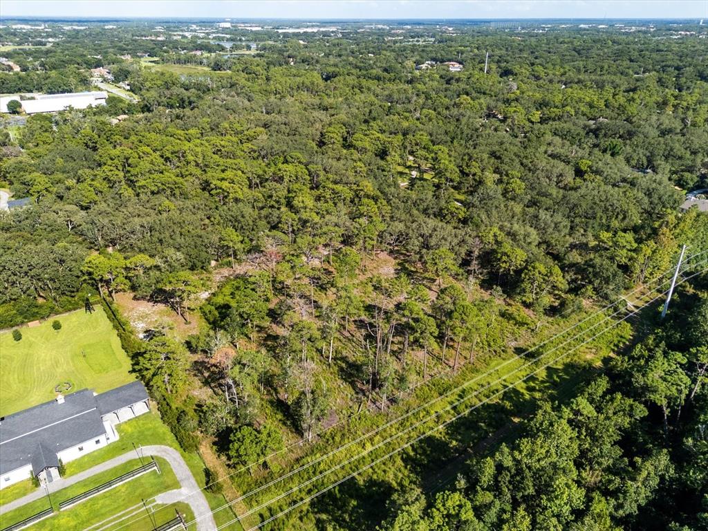 An aerial view shows a large, wooded lot adjacent to a house and power lines — MARKHAM WOODS ROAD, LAKE MARY, FL