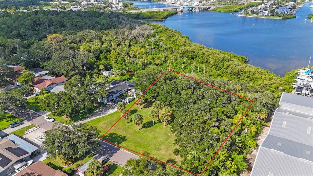 An aerial view shows a vacant, partially wooded residential lot outlined in red near water — 145TH LANE, LARGO, FL