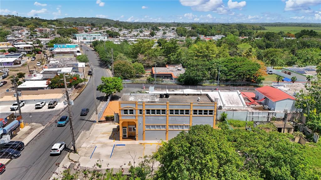 An aerial view shows a two-story commercial building with orange trim next to a road — 16 GUARICO AVENUE, VEGA BAJA, PR
