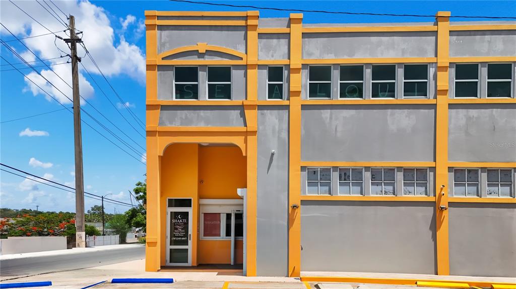 A two-story commercial building with gray stucco walls, orange trim, and a ground-floor entrance — 16 GUARICO AVENUE, VEGA BAJA, PR