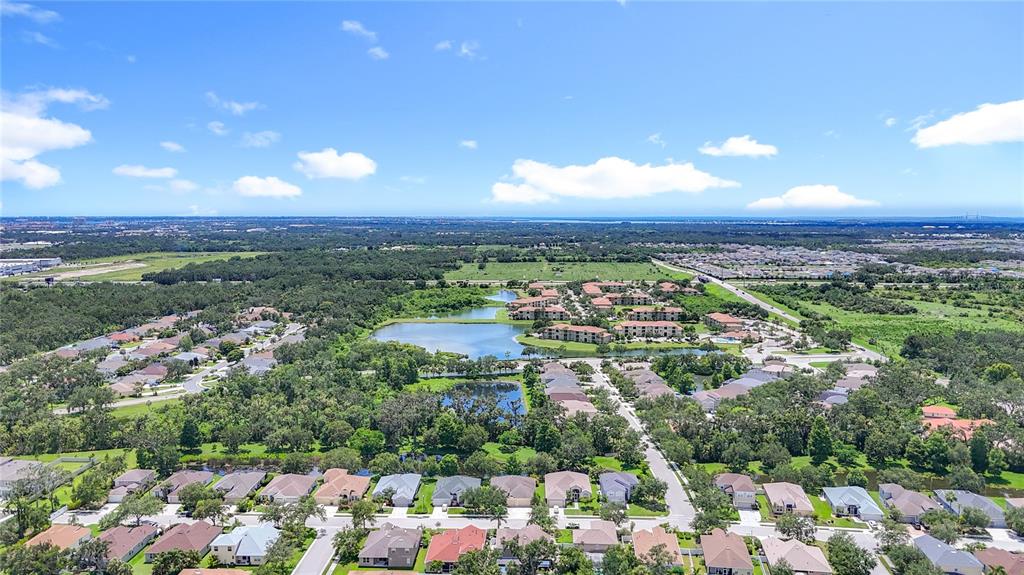 An aerial view shows a residential neighborhood with houses, apartment buildings, and several ponds — 3409 61ST TERRACE E, ELLENTON, FL