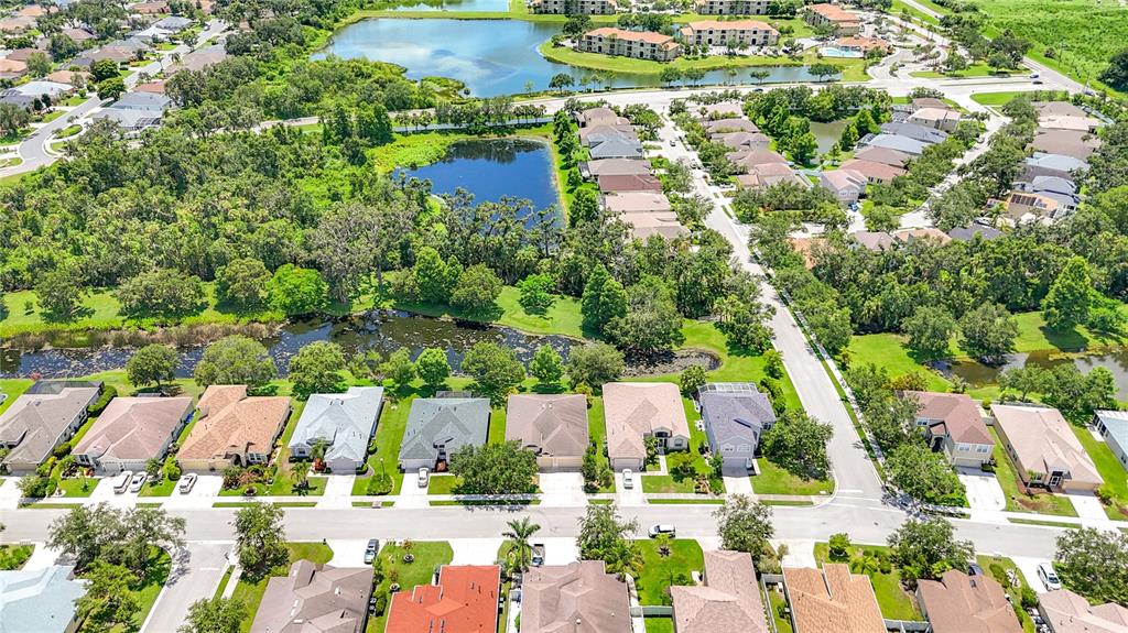 An aerial view shows a suburban neighborhood with houses, streets, and several ponds — 3409 61ST TERRACE E, ELLENTON, FL