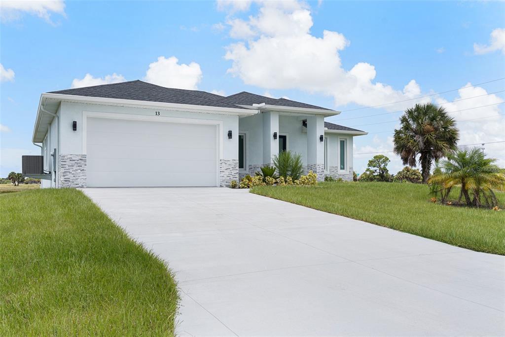 A light blue single-story house with a two-car garage and stone veneer accents — 13 TEAK LANE, PLACIDA, FL