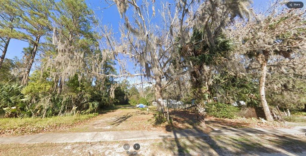 A vacant, wooded residential lot features mature trees draped in Spanish moss along a sidewalk — N/A, EAST PALATKA, FL