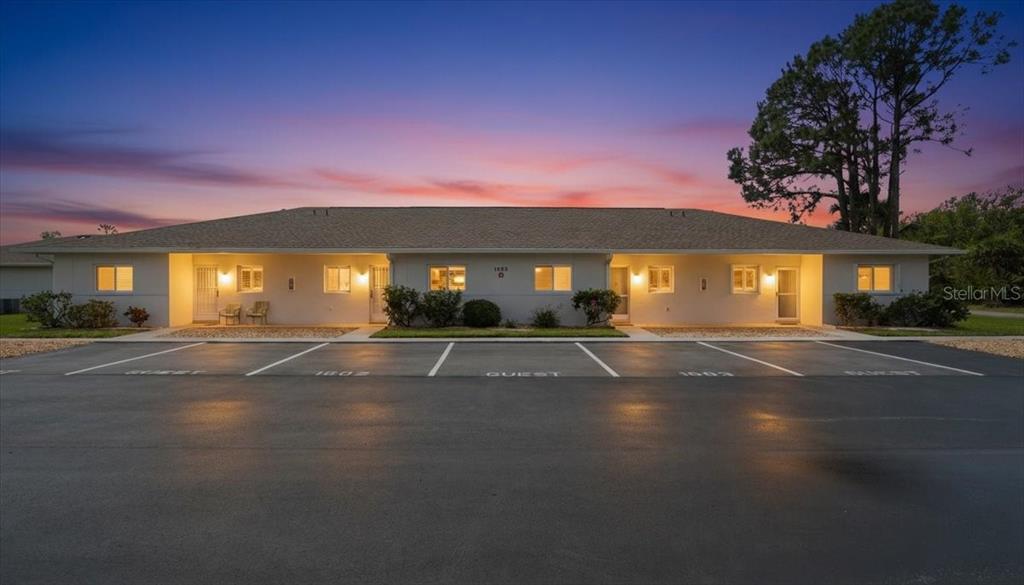 A single-story multi-unit building with a parking lot in the foreground at sunset — 12538 SW KINGSWAY CIRCLE UNIT 1503, LAKE SUZY, FL