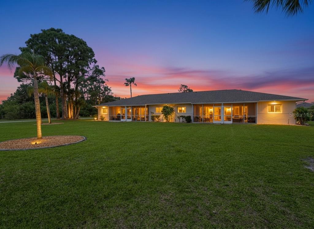 The exterior of a single-story house with a screened-in porch at sunset — 12538 SW KINGSWAY CIRCLE UNIT 1503, LAKE SUZY, FL