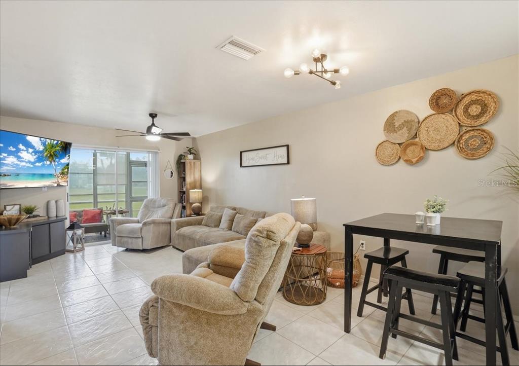 This living and dining area features tile flooring, a ceiling fan, and wall-mounted basket decor — 12538 SW KINGSWAY CIRCLE UNIT 1503, LAKE SUZY, FL