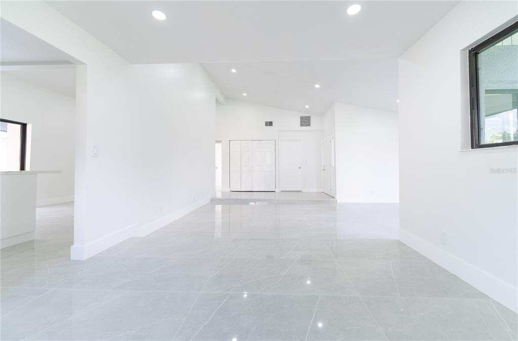 A bright, open-concept living area features white walls, recessed lighting, and polished gray tile flooring — 848 E FLAG LANE, KISSIMMEE, FL