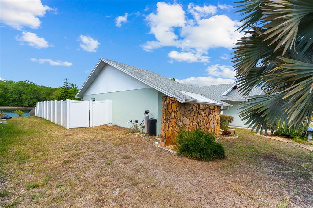 The exterior of a house features a stone accent wall, light green siding, and a fence — 10116 LANDMARK DRIVE, HUDSON, FL