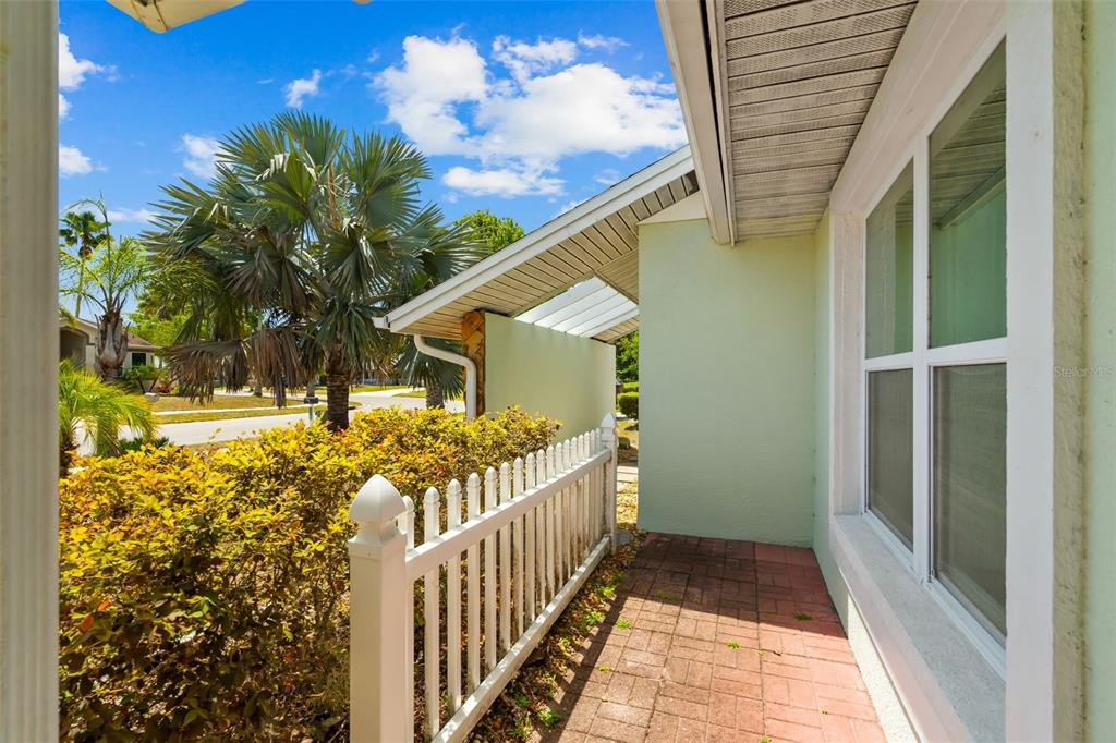 A paved walkway runs alongside a house with a white picket fence and palm trees — 10116 LANDMARK DRIVE, HUDSON, FL