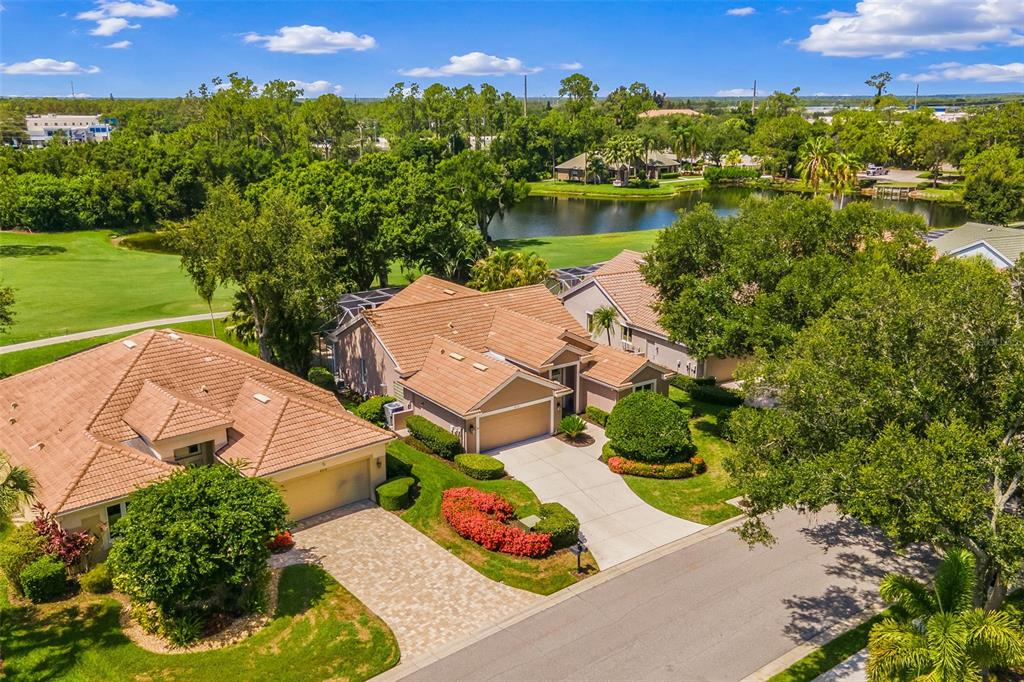 An aerial view shows two suburban houses with tile roofs, driveways, and landscaped yards — 8718 54TH AVENUE E, BRADENTON, FL