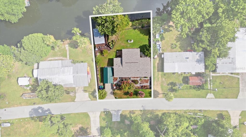 An aerial view shows a house with a green-roofed carport and a backyard facing water — 8421 W SCOTT COURT, HOMOSASSA, FL