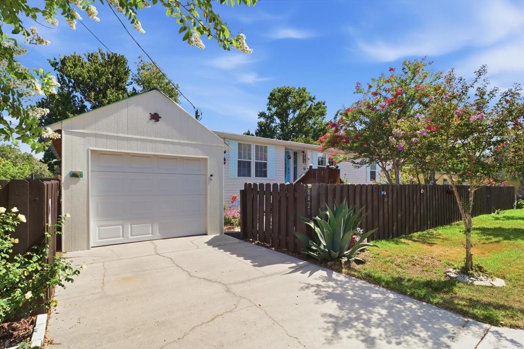 A single-story house with a white garage, a brown wooden fence, and a concrete driveway — 8421 W SCOTT COURT, HOMOSASSA, FL