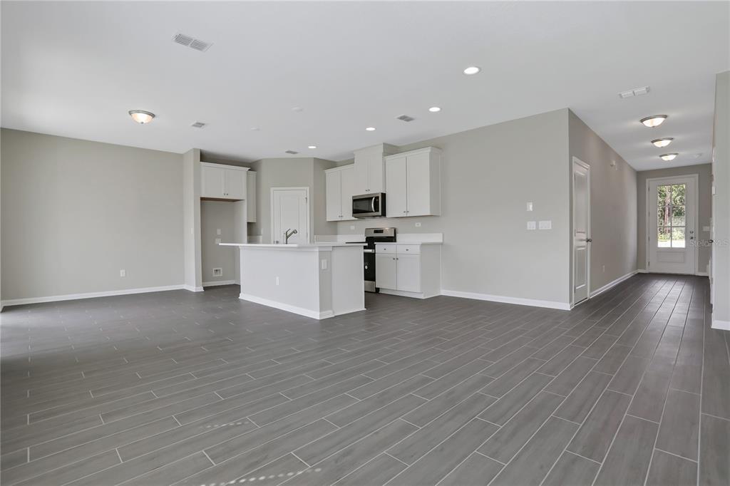 An open-concept kitchen features white cabinetry, a central island, and gray wood-look tile flooring — 377 BROOK FOREST DRIVE, ST AUGUSTINE, FL