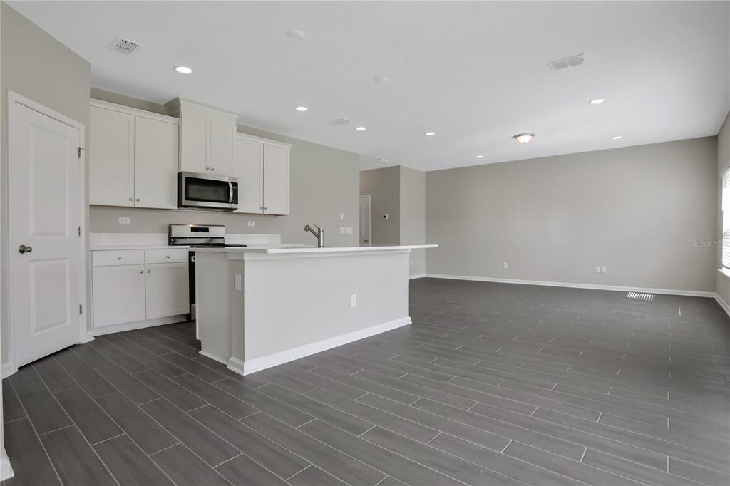 A kitchen with white cabinets and a center island opens into a spacious living area — 377 BROOK FOREST DRIVE, ST AUGUSTINE, FL