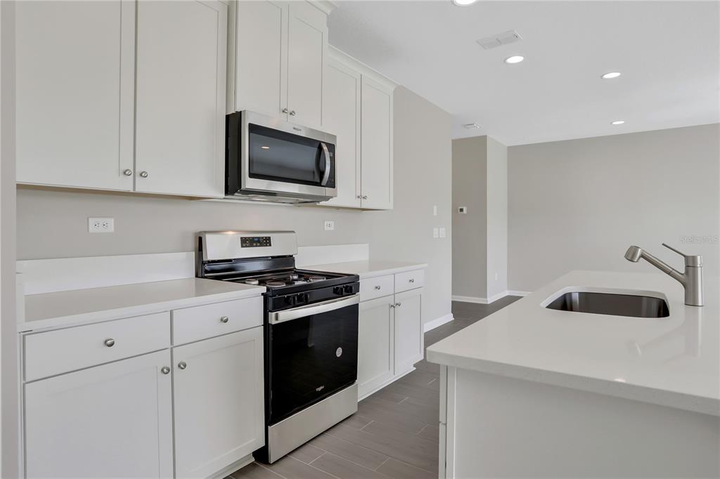 A modern kitchen features white cabinets, stainless steel appliances, and a central island with a sink — 377 BROOK FOREST DRIVE, ST AUGUSTINE, FL