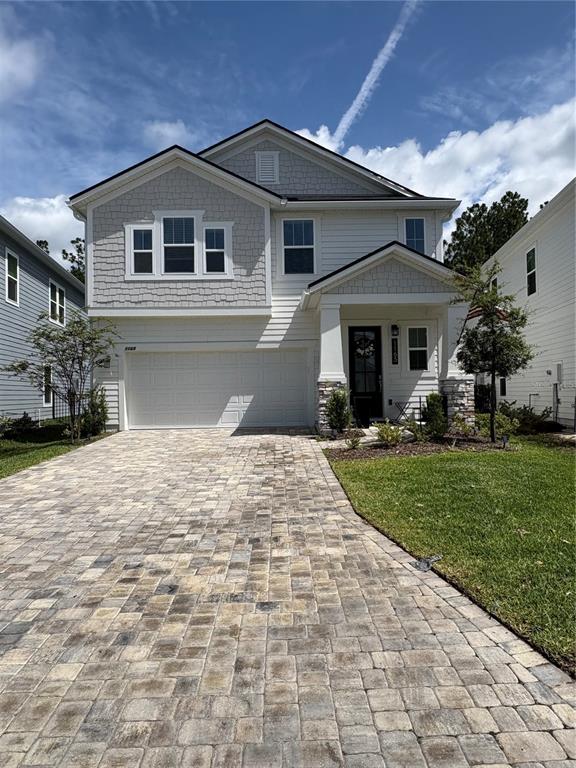 A two-story house with a paved driveway, light siding, and a front-facing garage — 1165 BROOK FOREST DRIVE, ST AUGUSTINE, FL