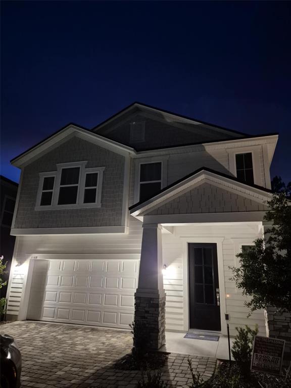 A two-story house exterior at night with a garage, stone-accented porch, and shingle siding — 1165 BROOK FOREST DRIVE, ST AUGUSTINE, FL