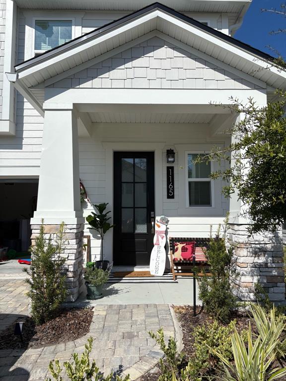 A front porch with stone pillars, a black door, and a snowman welcome sign — 1165 BROOK FOREST DRIVE, ST AUGUSTINE, FL