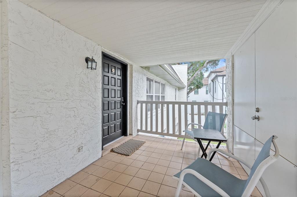 A covered balcony features tiled flooring, a black front door, and a small bistro set — 4614 W FIG STREET UNIT B, TAMPA, FL