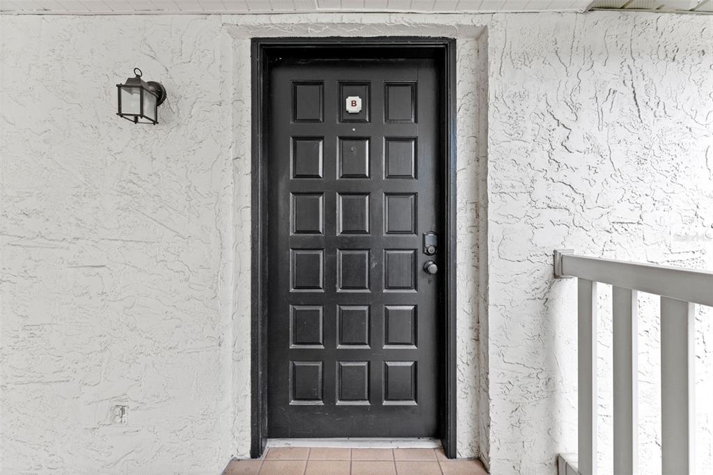 A black paneled front door with a letter B label sits in a textured wall — 4614 W FIG STREET UNIT B, TAMPA, FL