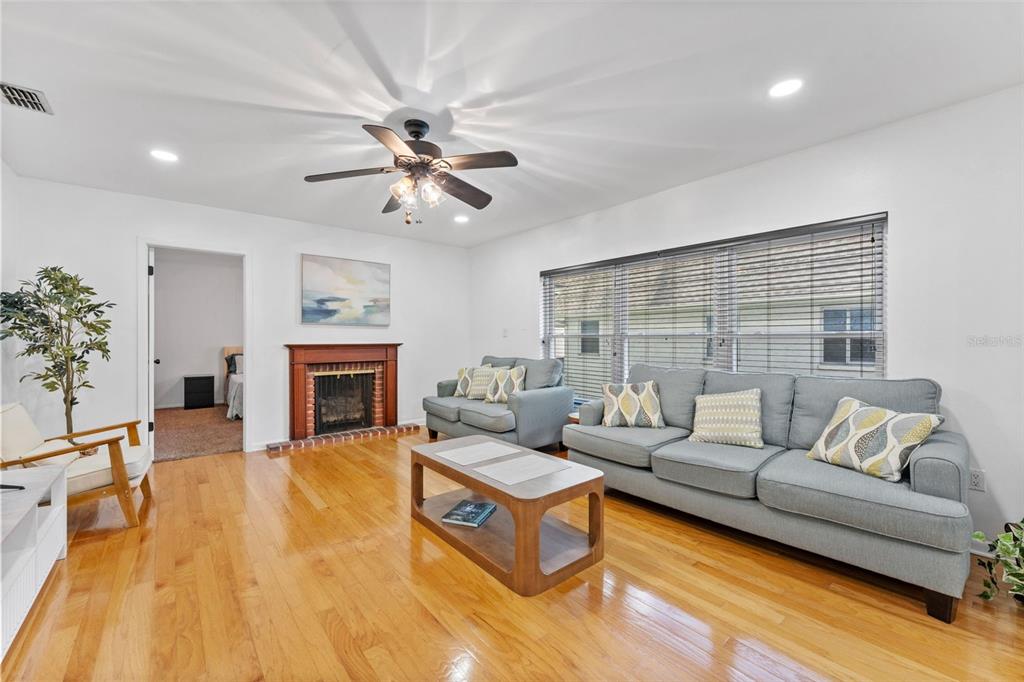 A living room with hardwood floors, a fireplace, a ceiling fan, and gray sofas — 4614 W FIG STREET UNIT B, TAMPA, FL