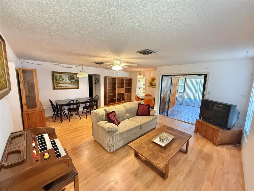 A living room with light wood flooring, a sofa, a coffee table, and a piano — 3112 VIVIENDA BOULEVARD, BRADENTON, FL
