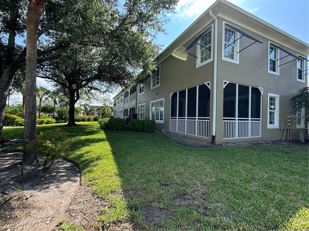 The exterior of a multi-story building features a screened-in porch and a grassy lawn — 10600 LEMON CREEK LOOP UNIT 101, ENGLEWOOD, FL