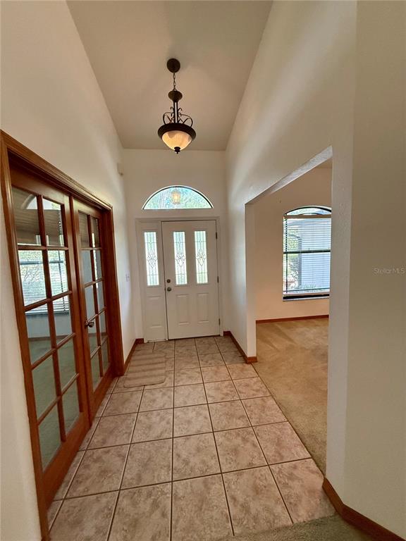 An empty dining room features beige carpeting, a vaulted ceiling, and a hanging chandelier — 4843 CALASANS AVENUE, ST CLOUD, FL