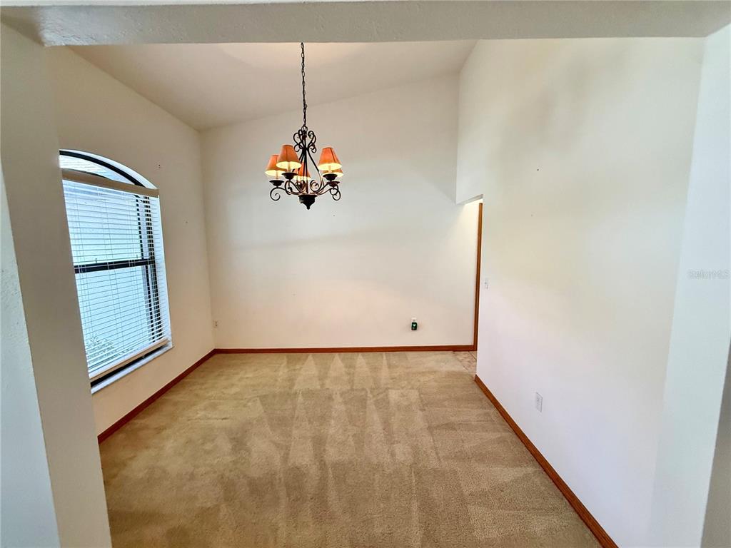 An empty room features beige carpet, a ceiling fan, an arched window, and French doors — 4843 CALASANS AVENUE, ST CLOUD, FL
