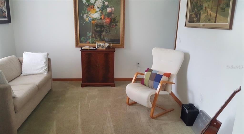 A spacious living room features beige carpeting, a vaulted ceiling, and sliding glass doors — 4843 CALASANS AVENUE, ST CLOUD, FL