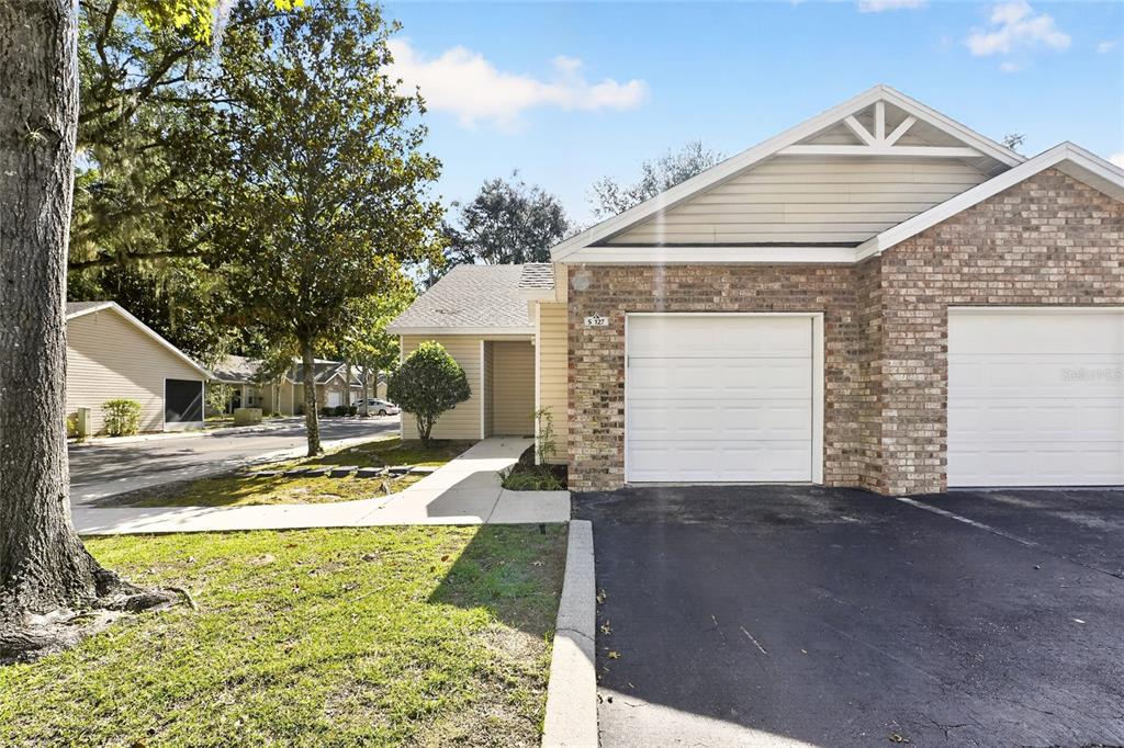 A beige vinyl-sided house with a screened porch sits near a parking lot and trees — 4700 SW ARCHER ROAD UNIT S-127, GAINESVILLE, FL