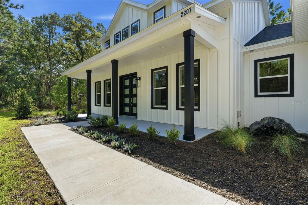 This is an architectural rendering of the front exterior of a modern farmhouse-style home — 2207 COUNTY ROAD 243E, WILDWOOD, FL