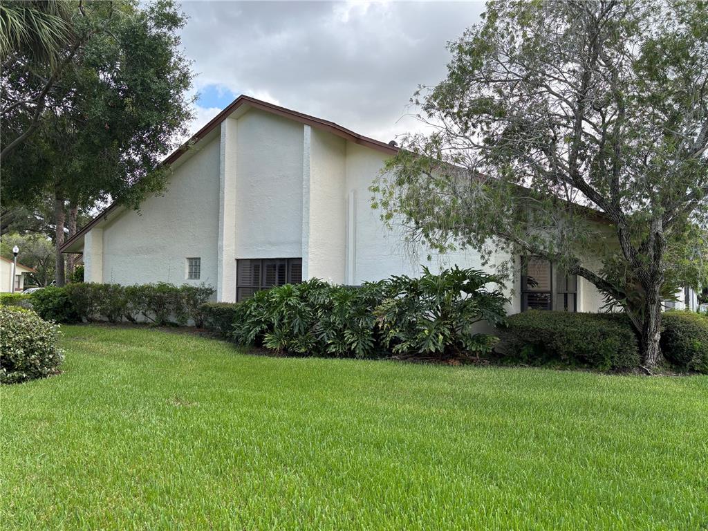 A side view of a white stucco house with a gabled roof and landscaping — 14837 FEATHER COVE LANE UNIT 45, CLEARWATER, FL