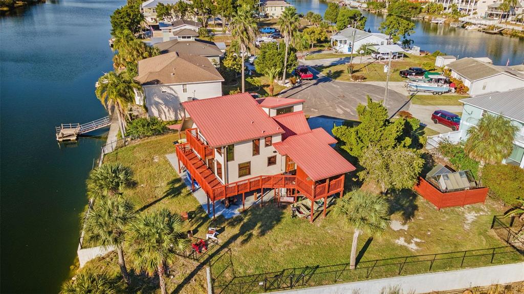 An aerial view of a multi-level house with a red metal roof near a canal — 3179 AZALEA DRIVE, HERNANDO BEACH, FL