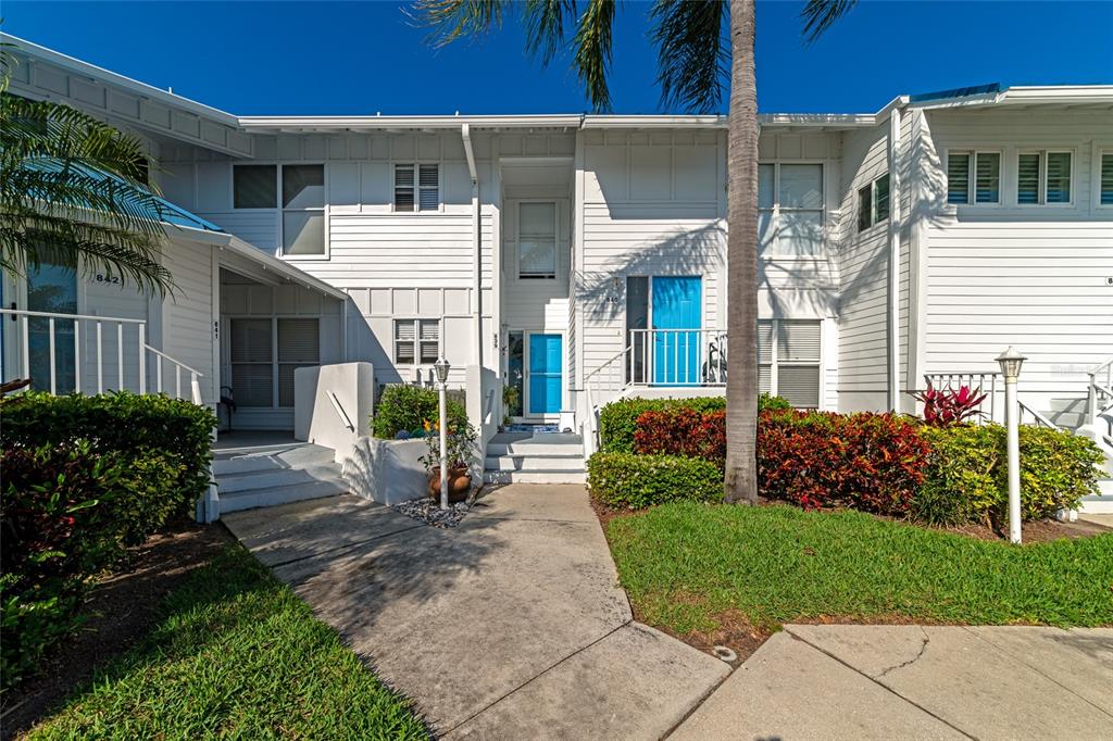 Exterior view of a white two-story townhouse complex with blue doors and landscaped front yards — 839 AUDUBON DRIVE UNIT 839, BRADENTON, FL