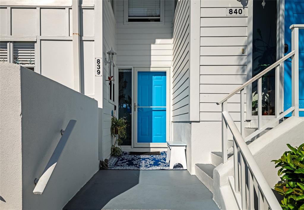 The exterior entrance features a bright blue door, a white staircase, and a patterned rug — 839 AUDUBON DRIVE UNIT 839, BRADENTON, FL