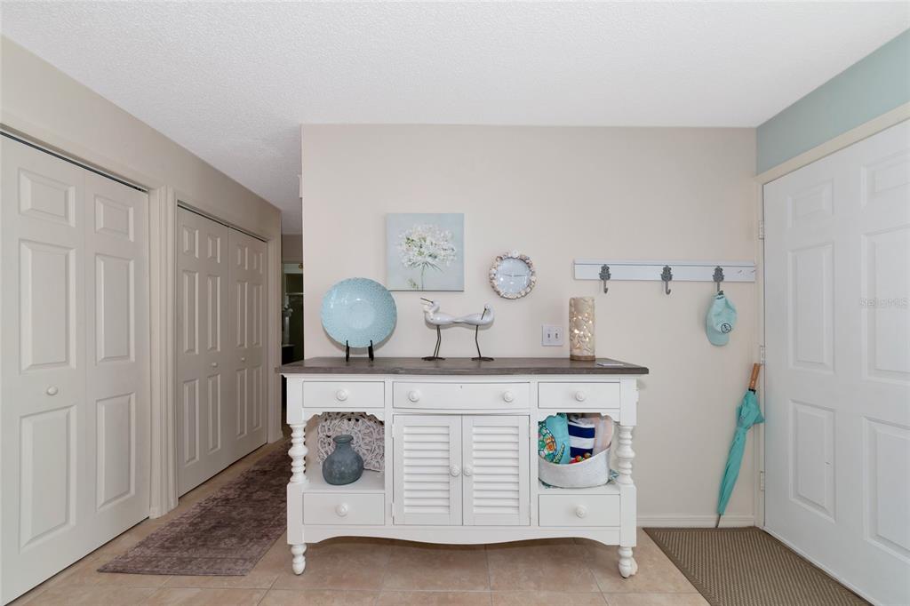 A white wooden console table sits in a tiled entryway with a light blue umbrella — 839 AUDUBON DRIVE UNIT 839, BRADENTON, FL