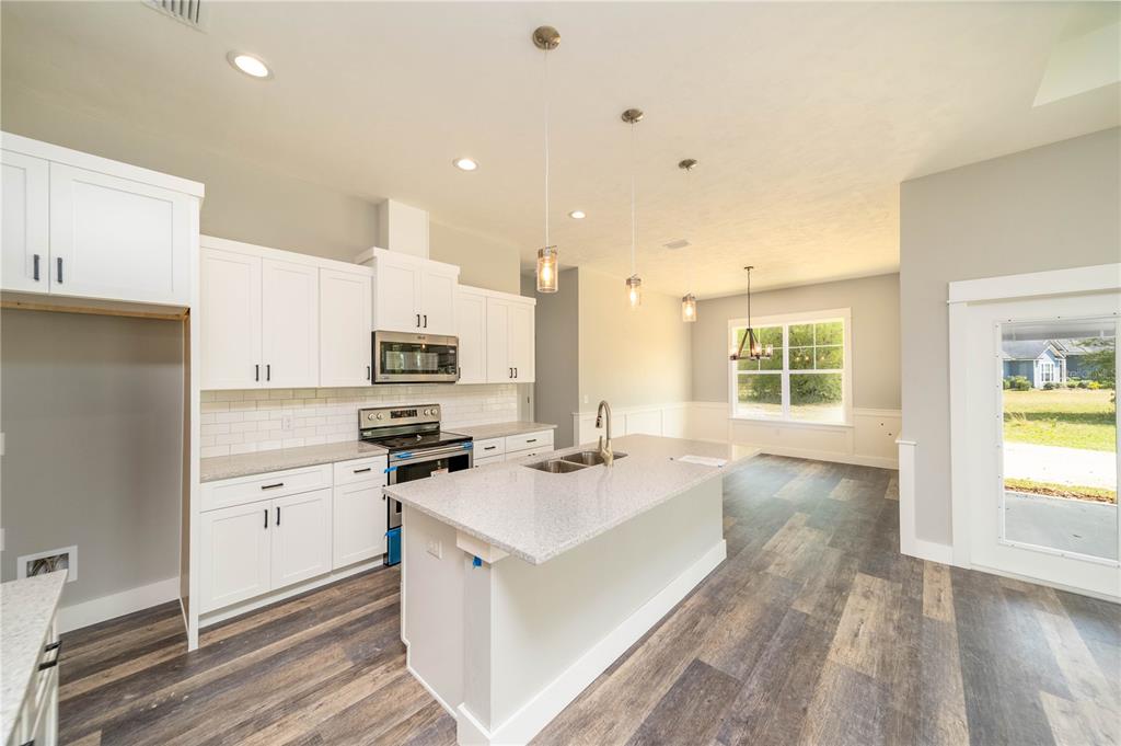 A modern kitchen features white cabinets, a granite island, and wood-look flooring in an open space — TBD2 71ST LANE, O'BRIEN, FL