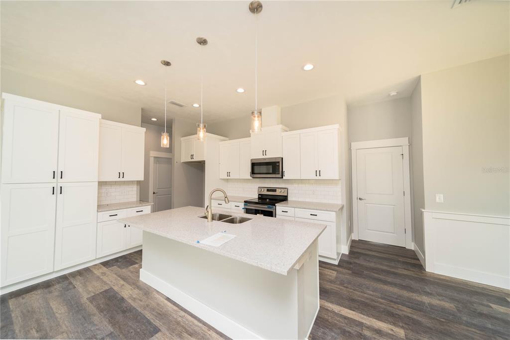 A kitchen features white cabinetry, a central island with a sink, and dark wood flooring — TBD2 71ST LANE, O'BRIEN, FL