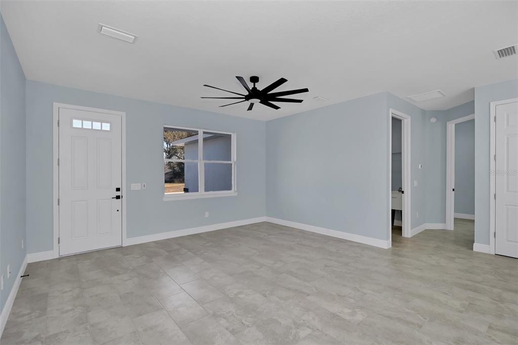 A light blue room features a white door, a window, a ceiling fan, and tiled floors — 7604 SW 103RD LOOP, OCALA, FL