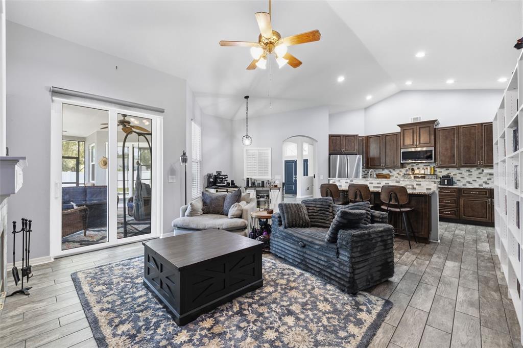An open-concept living room with a kitchen, dark wood cabinets, and tile flooring — 12020 RUNNING FOX CIRCLE, RIVERVIEW, FL