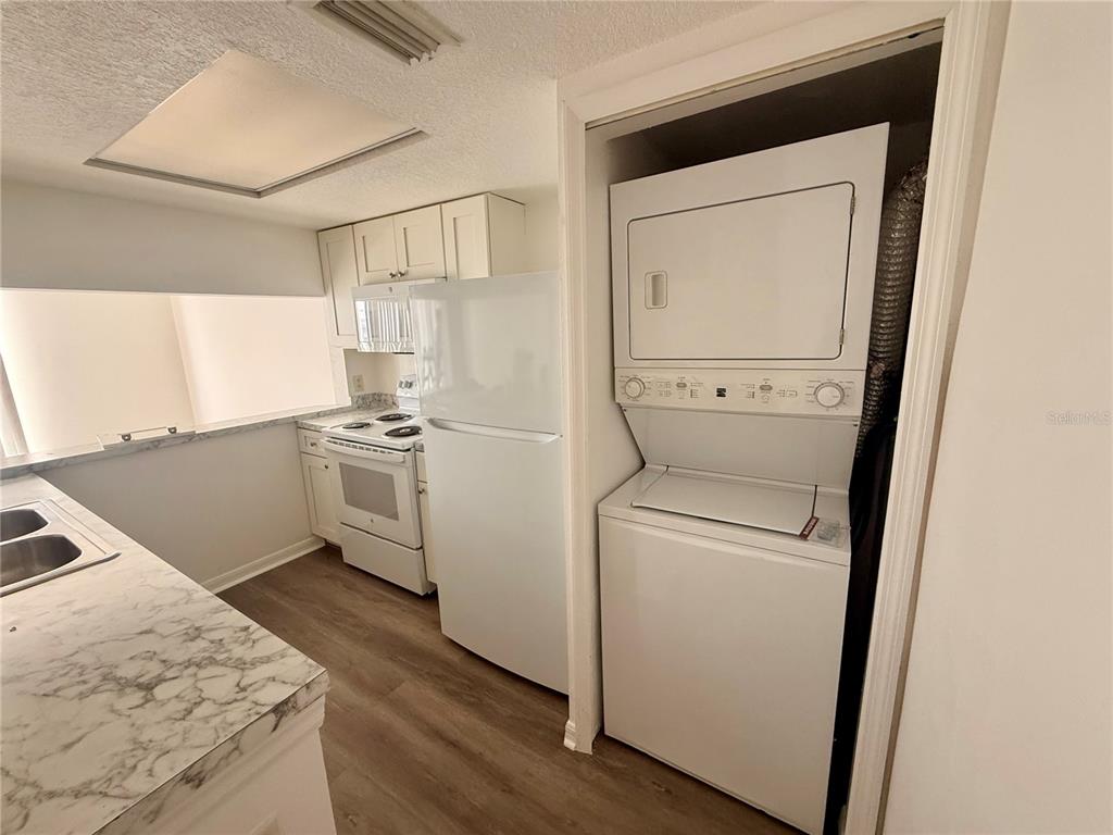A kitchen features white appliances, a stacked washer-dryer unit, and marble-patterned countertops — 862 CARIBBEAN DRIVE, DAVENPORT, FL